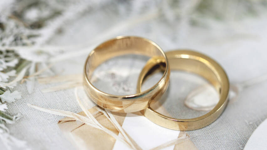 Two golden wedding rings, partially on top of each other.