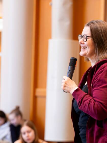 Työntekijä puhuu mikrofoniin ihmisten edessä.