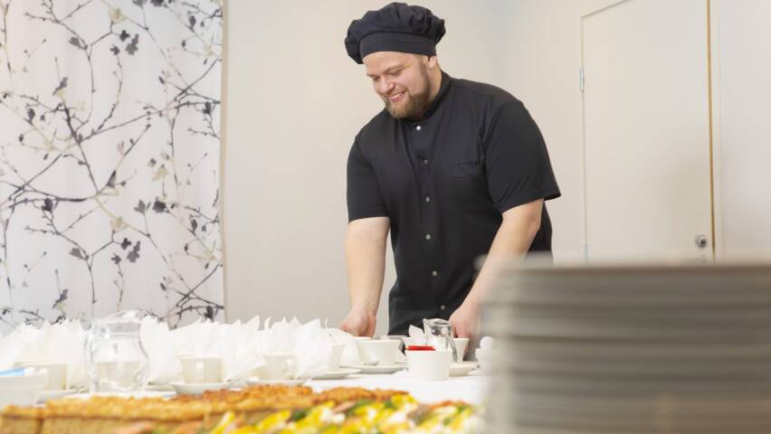 Pitopalvelussa asetellaan tarjottavia kahvitusta varten.