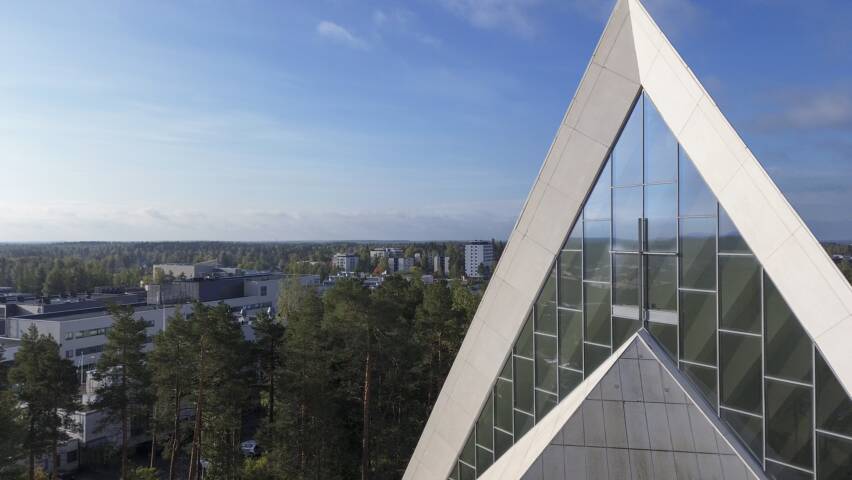 ilmakuva hyvinkään kirkon etupuolelta, sinistä taivasta vasten näkyy kirkon päätyikkunat ja risti.