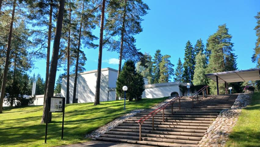 Rauhannummen krematoriorakennus ulkoa päin, edessä mäntyjä ja portaat.