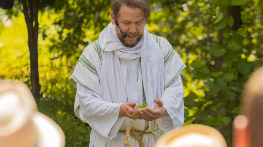 Timo Lappeteläinen valkoisessa kaavussa, mikrofoni kiinnitettynä.